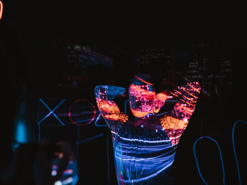 Person stretching in a dark room with neon orchid lights